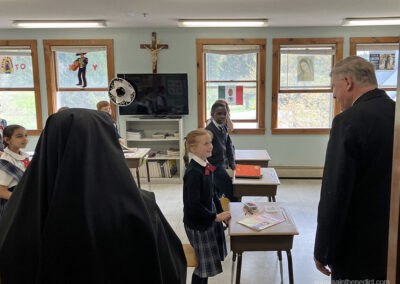 Third grade students greet the Bishop in their bright classroom.